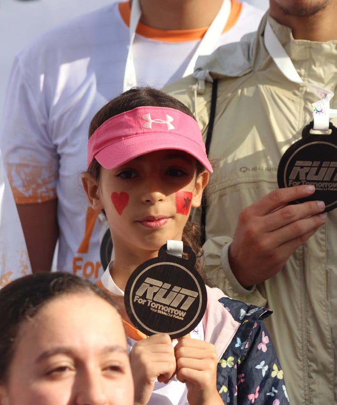 A young runner showing her medal