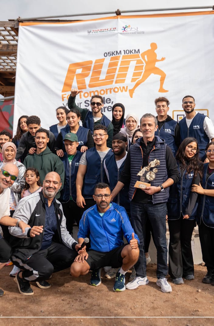 A company team gathered under the Run For Tomorrow arch